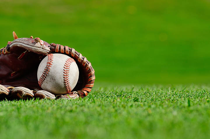 baseball glove with baseball in the grass